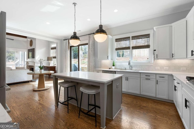 kitchen with a kitchen bar, a sink, dark wood finished floors, and decorative backsplash