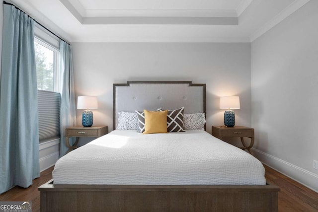 bedroom featuring baseboards, a tray ceiling, and wood finished floors