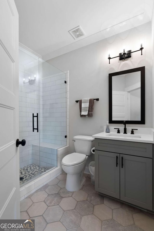 full bath with toilet, vanity, a shower stall, and visible vents