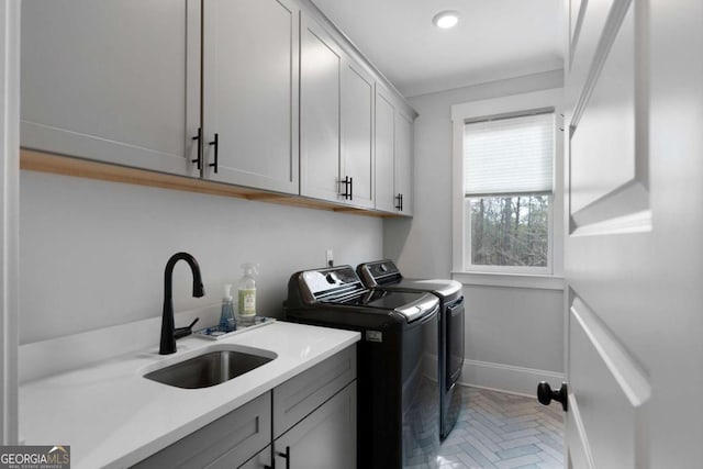 laundry area with cabinet space, baseboards, a sink, and independent washer and dryer