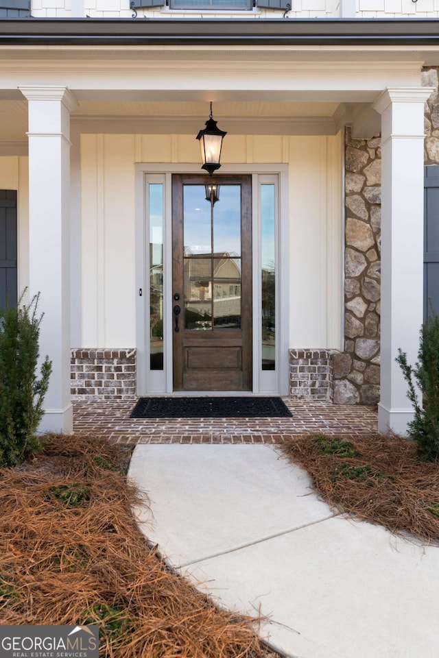 view of exterior entry featuring stone siding and a porch