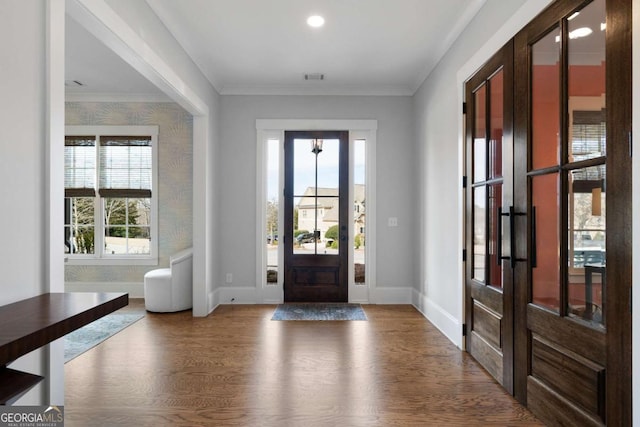 foyer entrance featuring baseboards, visible vents, ornamental molding, and wood finished floors