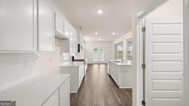 1039 Blue Juniper Cir, Loganville, GA 30052 - kitchen with gas stove, backsplash, dark wood-type flooring, stainless steel microwave, and light countertops