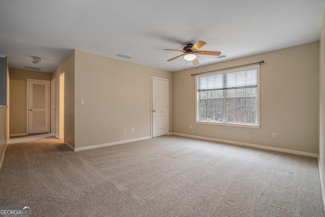 carpeted empty room with baseboards, visible vents, and ceiling fan