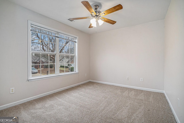 carpeted spare room featuring ceiling fan, visible vents, and baseboards