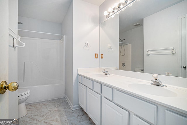 bathroom featuring marble finish floor, tub / shower combination, a sink, and toilet