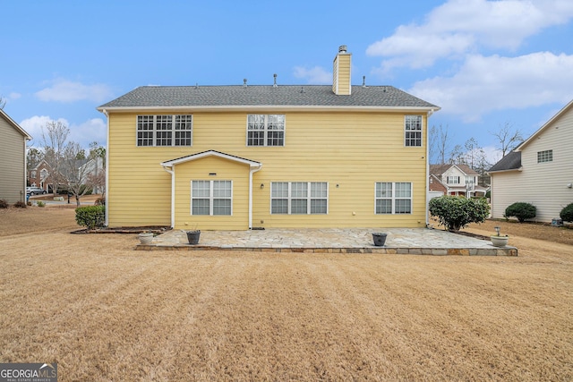 back of house featuring a patio, a yard, and a chimney