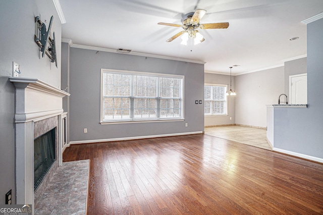 unfurnished living room featuring a fireplace, crown molding, visible vents, hardwood / wood-style floors, and baseboards