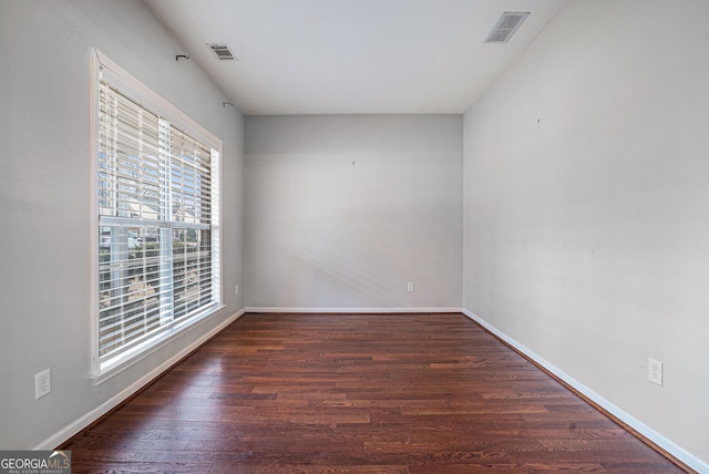 spare room featuring visible vents, baseboards, and wood finished floors