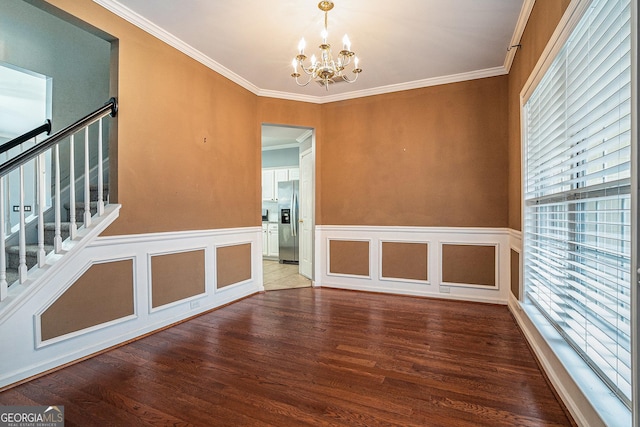 spare room featuring a chandelier, ornamental molding, stairway, and wood finished floors