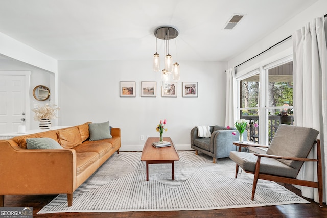 living area with visible vents, baseboards, and wood finished floors