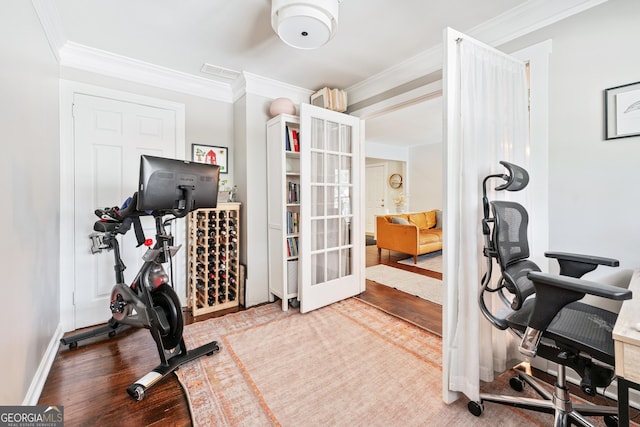 exercise area with french doors, wood finished floors, baseboards, and ornamental molding