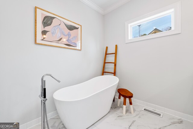 bathroom with visible vents, marble finish floor, ornamental molding, baseboards, and a soaking tub