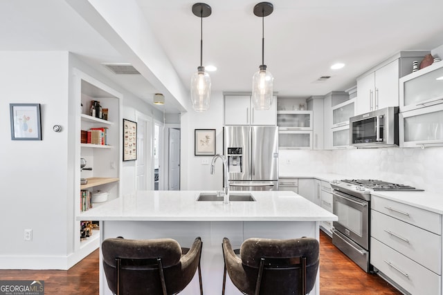 kitchen featuring a sink, stainless steel appliances, light stone countertops, and dark wood-style flooring