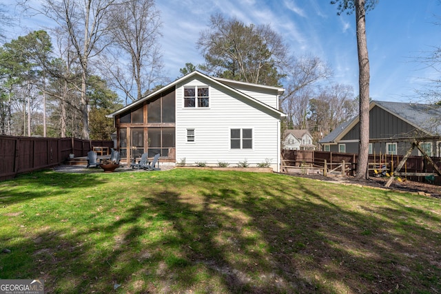 rear view of house with a patio area, a lawn, a fenced backyard, and a sunroom