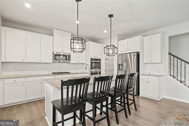 kitchen featuring backsplash, white cabinets, light wood-style floors, stainless steel appliances, and recessed lighting