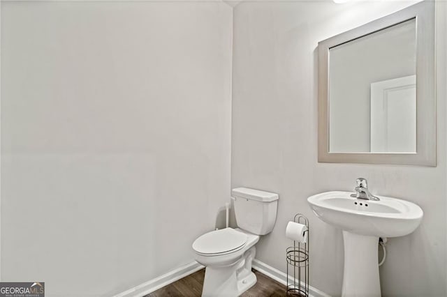 bathroom with baseboards, wood finished floors, and toilet