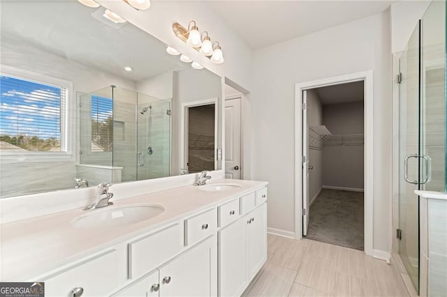 bathroom featuring double vanity, a spacious closet, a sink, and a stall shower