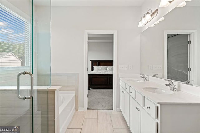 ensuite bathroom with connected bathroom, double vanity, a sink, and a bath