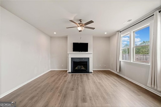 unfurnished living room featuring a ceiling fan, baseboards, light wood-type flooring, and a fireplace