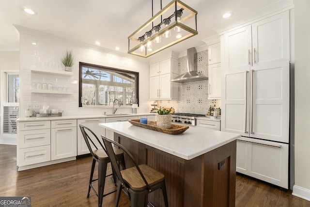 kitchen featuring dark wood-style flooring, a sink, wall chimney range hood, and backsplash