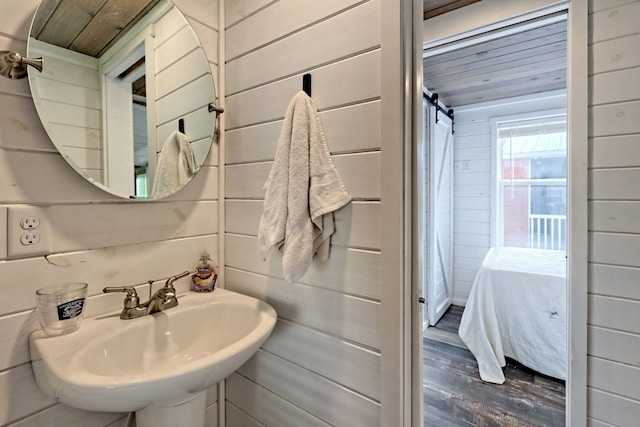 ensuite bathroom with ensuite bathroom, a sink, wooden walls, wood finished floors, and wooden ceiling