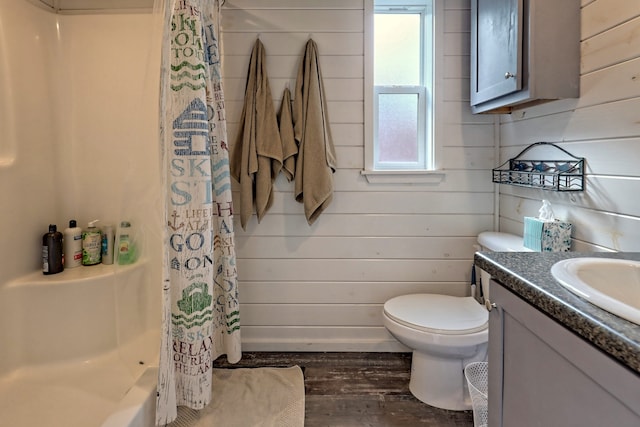 bathroom featuring wooden walls, toilet, a shower with curtain, wood finished floors, and vanity