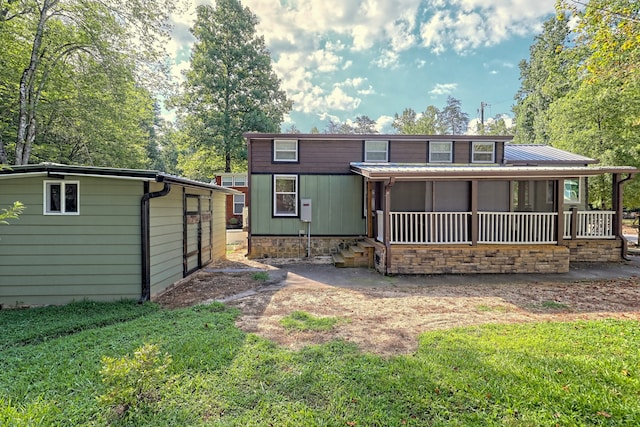 rear view of property featuring metal roof and a yard