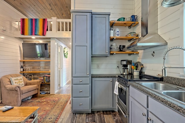 kitchen featuring wood walls, wall chimney exhaust hood, dark wood-style flooring, and gray cabinetry