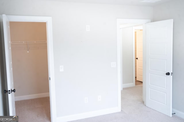 unfurnished bedroom with carpet floors, a spacious closet, a closet, and baseboards