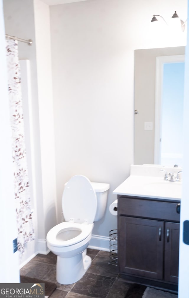 bathroom with a shower with curtain, baseboards, vanity, and toilet