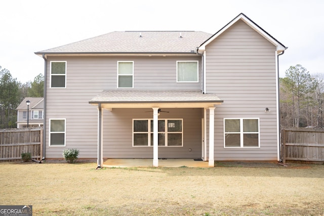 back of property with a shingled roof, a patio, ceiling fan, fence, and a yard