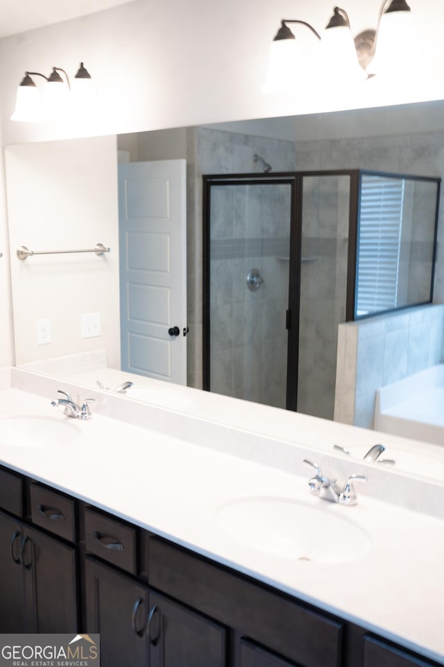 bathroom with double vanity, a stall shower, and a sink