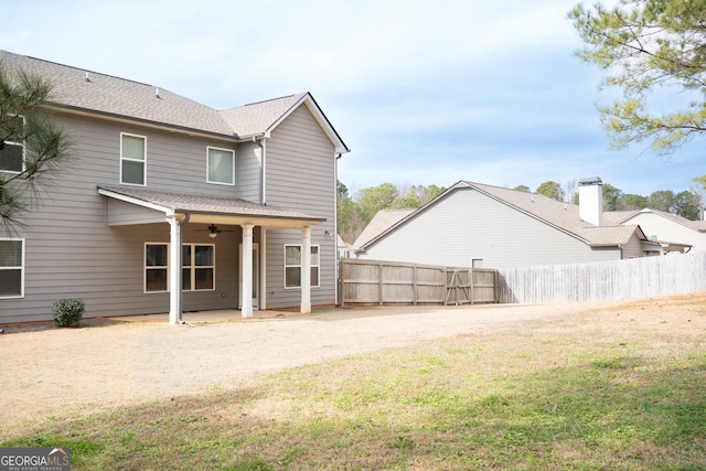 rear view of property featuring roof with shingles, a yard, a ceiling fan, a patio area, and fence