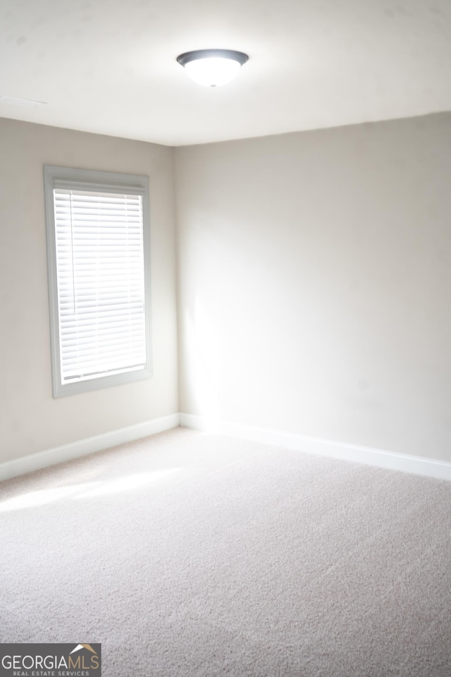 carpeted empty room featuring baseboards