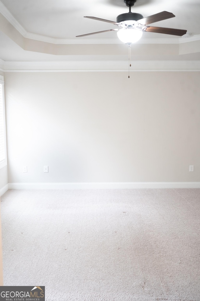 carpeted empty room featuring baseboards, ceiling fan, a tray ceiling, and crown molding