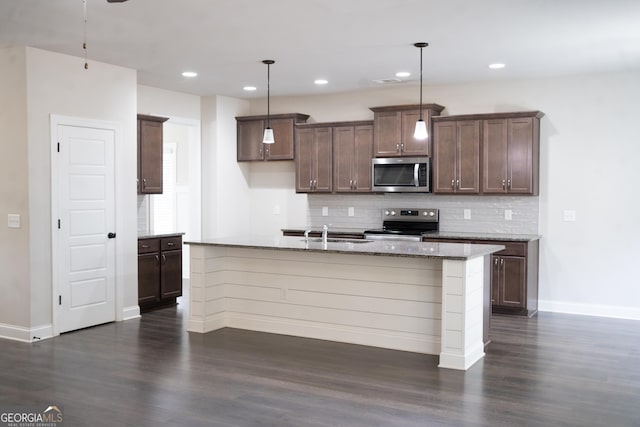 kitchen featuring dark wood-style floors, backsplash, appliances with stainless steel finishes, a kitchen island with sink, and a sink