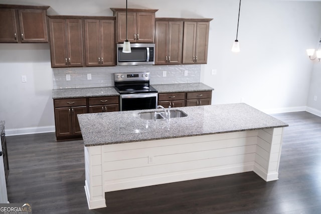 kitchen featuring appliances with stainless steel finishes, dark wood-style flooring, a sink, and decorative backsplash