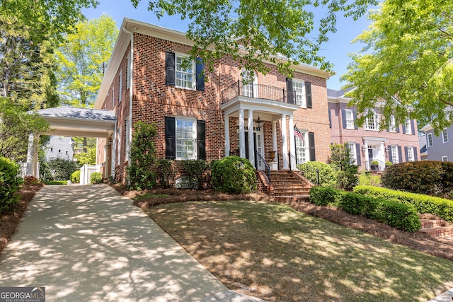 view of front of house featuring a carport, a balcony, and brick siding