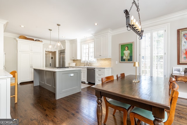 kitchen with appliances with stainless steel finishes, a kitchen island, light countertops, and ornamental molding