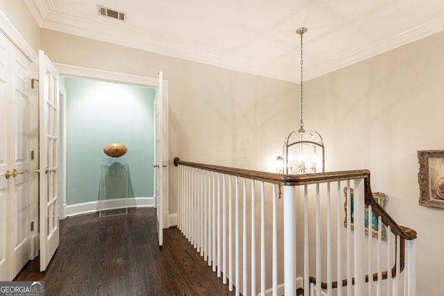 hall featuring visible vents, crown molding, dark wood-type flooring, baseboards, and a notable chandelier