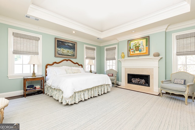 bedroom featuring a high end fireplace, visible vents, multiple windows, and a raised ceiling