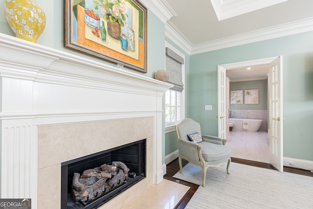 sitting room featuring wood finished floors, baseboards, a skylight, a high end fireplace, and crown molding