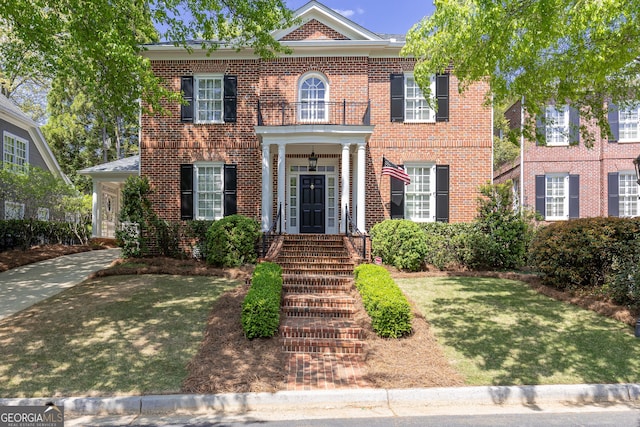 colonial inspired home with brick siding and a front lawn