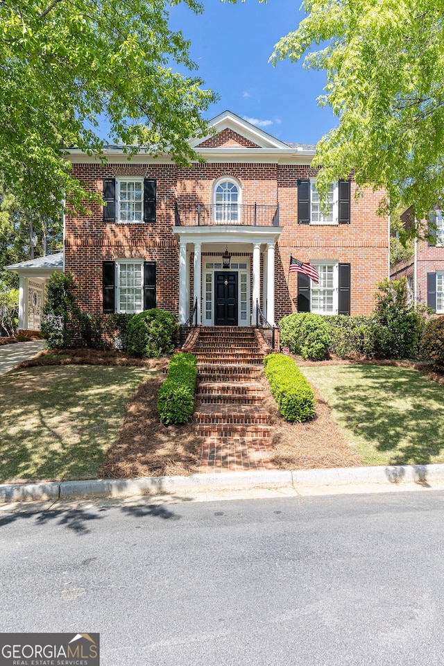 colonial-style house featuring a front lawn, french doors, and brick siding