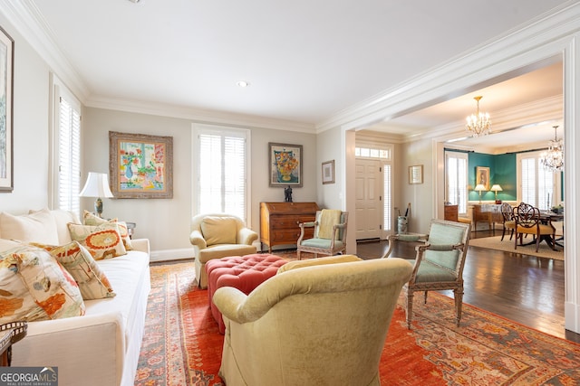 living area featuring an inviting chandelier, crown molding, wood finished floors, and a healthy amount of sunlight