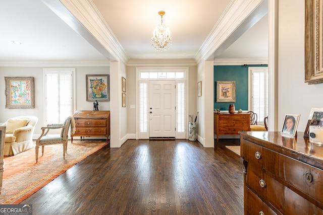 foyer entrance with a notable chandelier, dark wood-type flooring, and crown molding