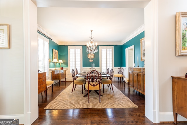 dining space with wainscoting, ornamental molding, an inviting chandelier, and dark wood-style flooring