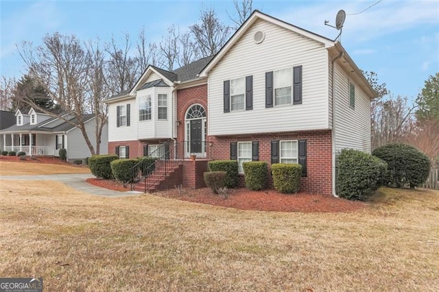 raised ranch with a front yard and brick siding