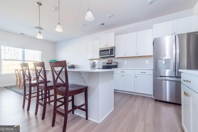 kitchen featuring stainless steel appliances, white cabinets, decorative backsplash, and a kitchen bar